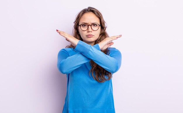 Mulher hispânica bonita parecendo irritada e cansada de sua atitude, dizendo o suficiente! mãos cruzadas na frente, dizendo para você parar