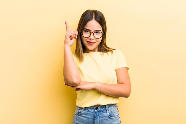 Mulher hispânica bonita se sentindo como um gênio segurando o dedo orgulhosamente no ar depois de perceber uma ótima ideia dizendo eureka