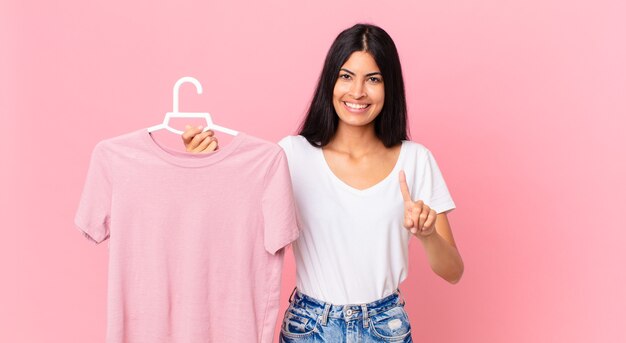 Mulher hispânica bonita sorrindo e parecendo amigável, mostrando o número um e segurando um pano escolhido