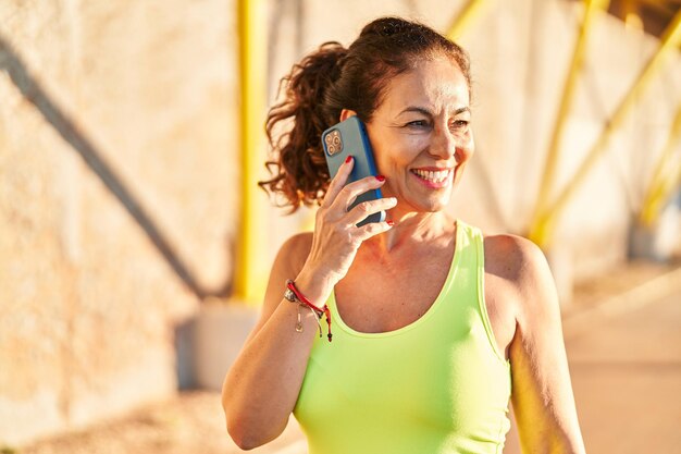 Mulher hispânica de meia-idade malhando falando ao telefone no passeio