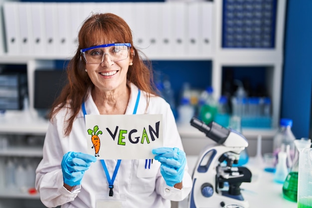 Mulher hispânica de meia idade trabalhando em laboratório vegano sorrindo com um sorriso feliz e legal no rosto mostrando os dentes