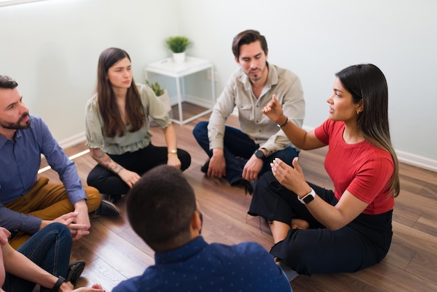 Mulher hispânica em seus 20 anos falando sobre seus sentimentos e emoções. Pessoas com vícios se reunindo para discutir seus problemas em um grupo de apoio