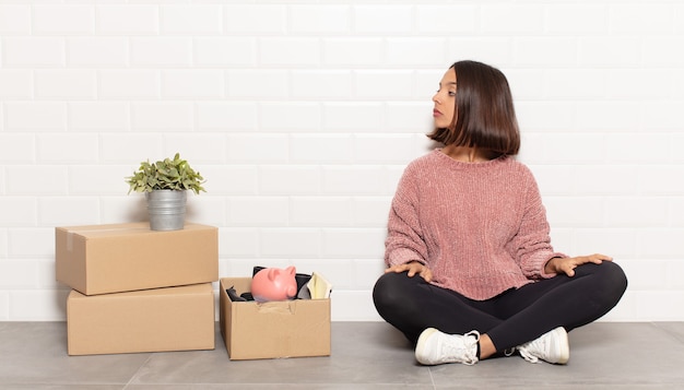 Mulher hispânica em vista de perfil olhando para copiar o espaço à frente, pensando, imaginando ou sonhando acordada