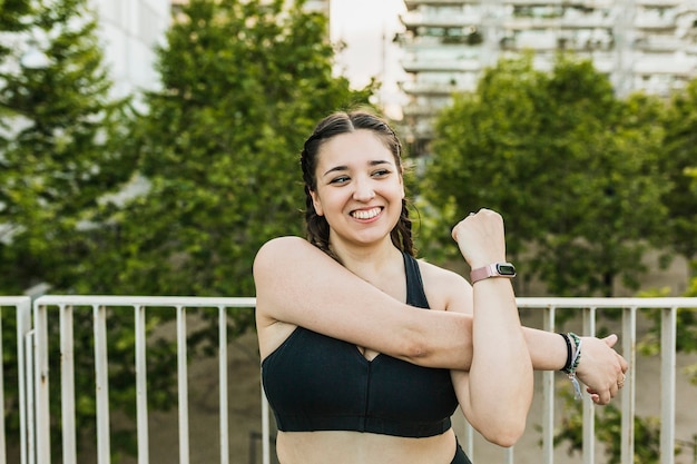 Mulher hispânica feliz esticando os braços antes do treino ao ar livre