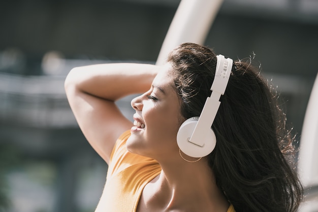 Mulher hispânica feliz usando fones de ouvido, ouvindo música