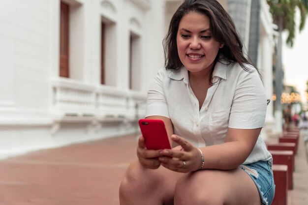 Mulher hispânica na cidade checando seu celular