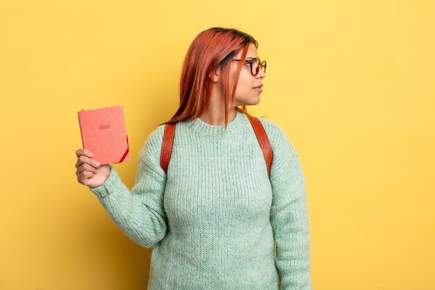 Mulher hispânica na vista de perfil pensando, imaginando ou sonhando acordado. conceito de estudante e calendário