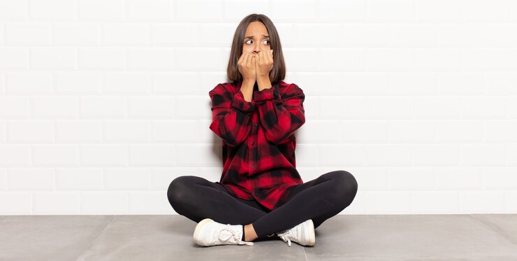 Foto mulher hispânica parecendo preocupada, ansiosa, estressada e com medo, roendo as unhas e olhando para o espaço da cópia lateral