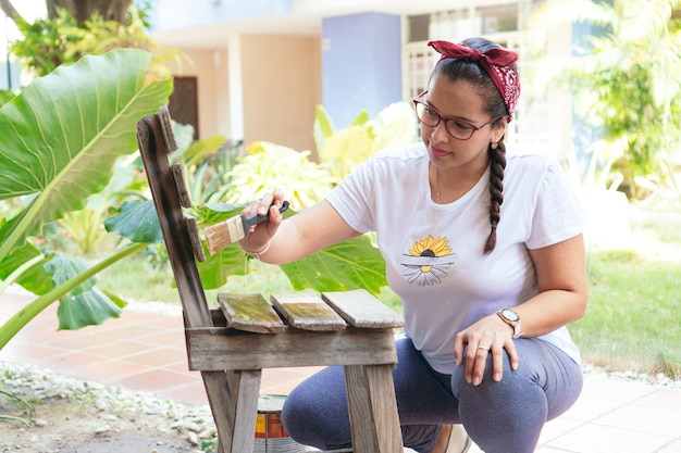 Mulher hispânica pintando móveis no quintal de sua casa