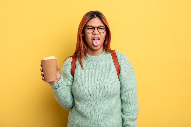 Mulher hispânica se sentindo enojada e irritada e com a língua de fora. estudante com um conceito de café