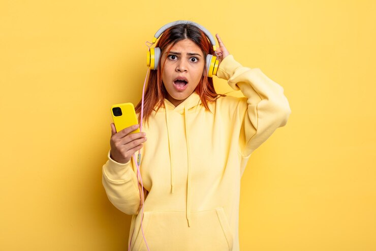 Foto mulher hispânica se sentindo estressada, ansiosa ou assustada com as mãos nos fones de ouvido e conceito de smartphone