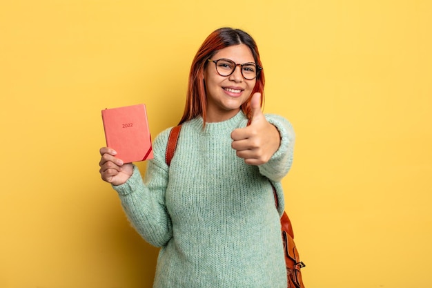 Mulher hispânica se sentindo orgulhosa sorrindo positivamente com polegares para cima estudante e conceito de calendário