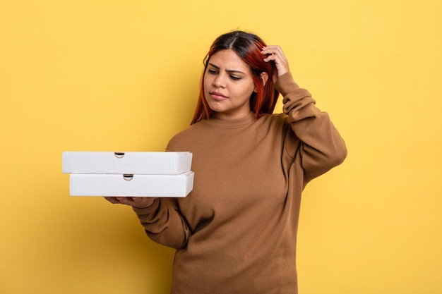 Mulher hispânica sorrindo alegremente e sonhando acordado ou duvidando do conceito de pizzas