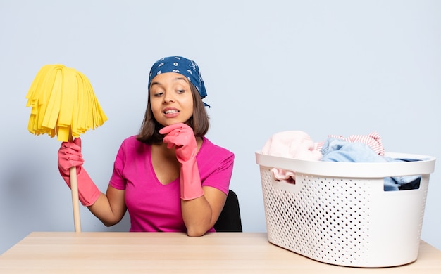 Mulher hispânica sorrindo com uma expressão feliz e confiante com a mão no queixo, pensando e olhando para o lado