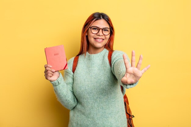 Mulher hispânica sorrindo e parecendo amigável mostrando o conceito de estudante e calendário número quatro