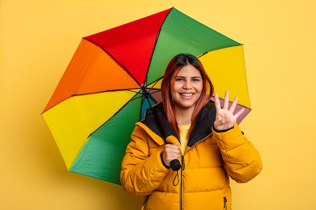 Mulher hispânica sorrindo e parecendo amigável, mostrando o número quatro. conceito de chuva e guarda-chuva