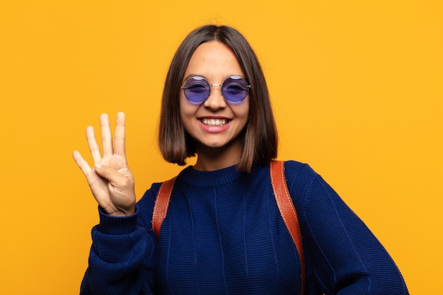 Mulher hispânica sorrindo e parecendo amigável, mostrando o número quatro ou o quarto com a mão para a frente, em contagem regressiva