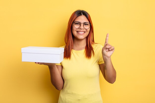 Mulher hispânica sorrindo e parecendo amigável, mostrando o número um. conceito de embalagem vazia