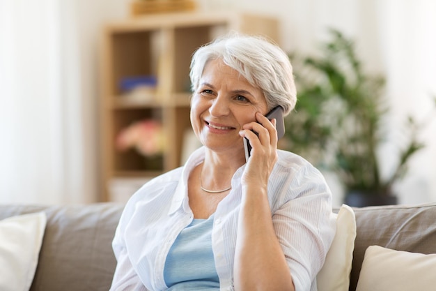 Mulher idosa a ligar para o smartphone em casa.
