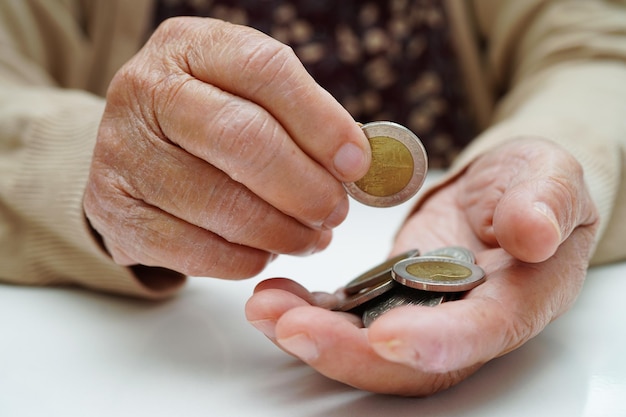 Mulher idosa aposentada contando dinheiro com moedas e se preocupando com despesas mensais e pagamento de taxa de tratamento