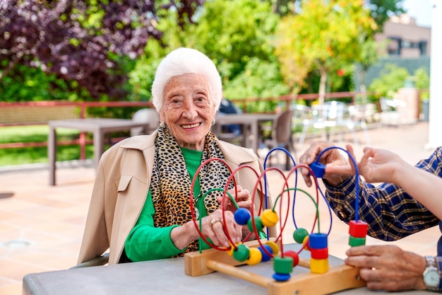 Foto mulher idosa aprimorando a destreza das mãos jogando o jogo infantil no pátio geriátrico em um dia ensolarado