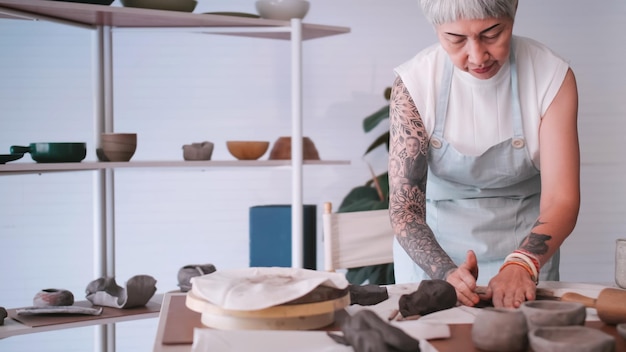 Mulher idosa asiática desfrutando do trabalho de cerâmica em casa Uma ceramista feminina está fazendo nova cerâmica em um estúdio