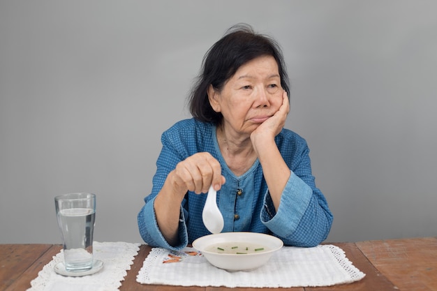 Mulher idosa asiática entediada com a comida