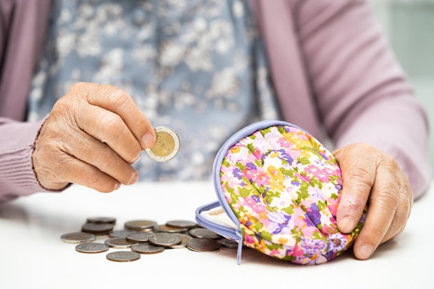 Mulher idosa asiática segurando dinheiro contando moedas na bolsa Problema de poupança de pobreza na aposentadoria