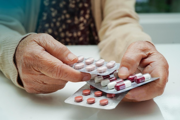 Mulher idosa asiática segurando pílula droga na mão forte conceito médico saudável