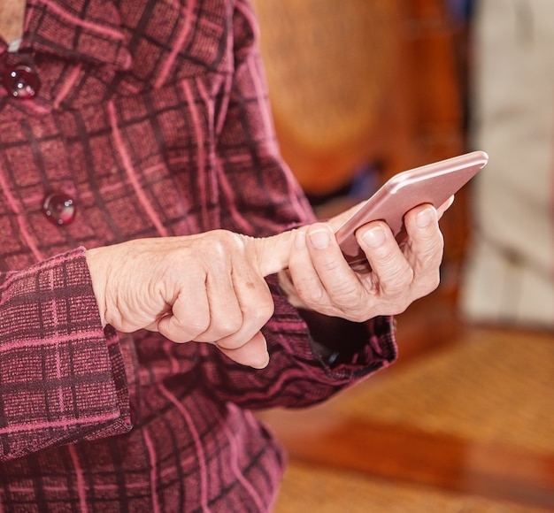 Mulher idosa asiática sentada e olhando no smartphone