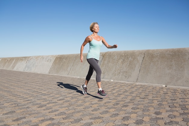 Mulher idosa ativa jogging no cais