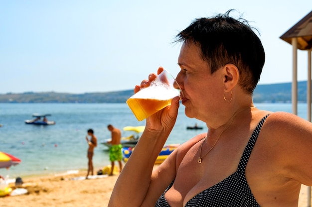 Mulher idosa bebendo cerveja na praia