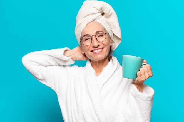 Mulher idosa bonita vestindo roupão de banho e tomando um café