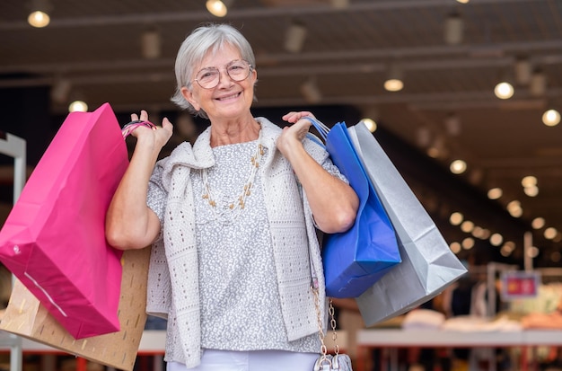 Foto mulher idosa caucasiana carregando sacolas de compras desfrutando do conceito de cliente de vendas de consumismo de compras