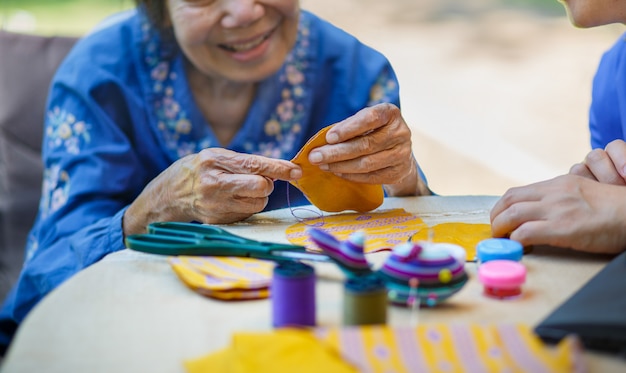 Mulher idosa com cuidador na terapia ocupacional de artesanato com agulha