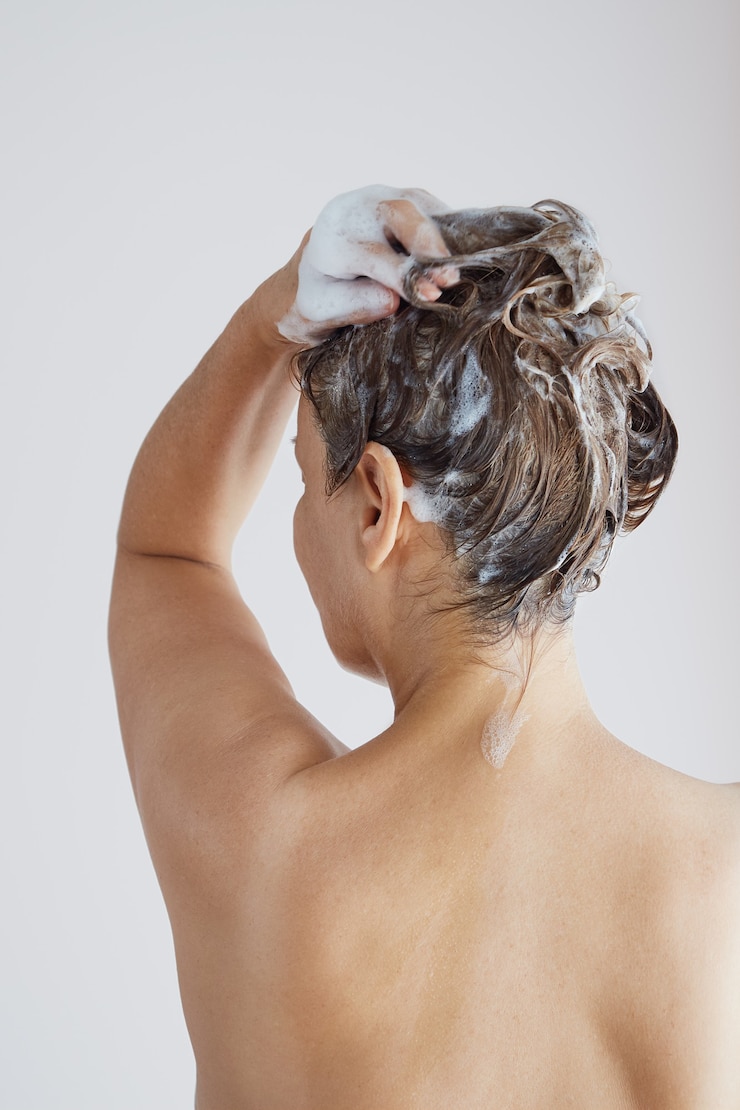 Foto mulher idosa com ombros nus lavando o cabelo com shampoo pelas costas