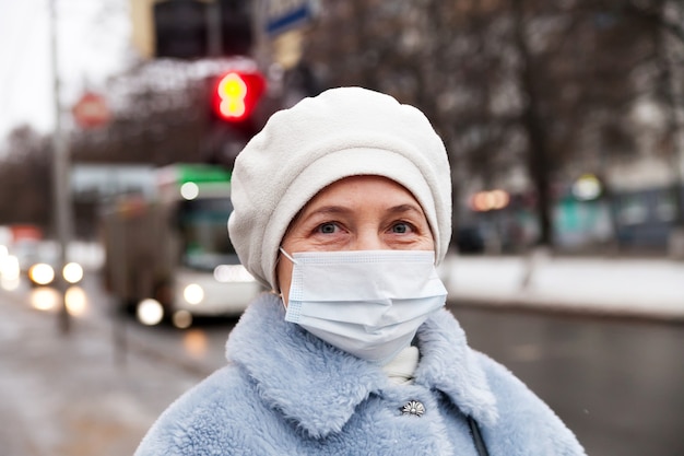 Mulher idosa com roupas de inverno e máscara médica na rua. O tema da proteção durante um surto de coronavírus