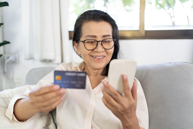 Mulher idosa com telefone inteligente para compras on-line Mão segurando telefone móvel com Pagamento com cartão de crédito compras on- line carteira eletrônica Pagamento Compras por telefone e conceito de cartão conectado