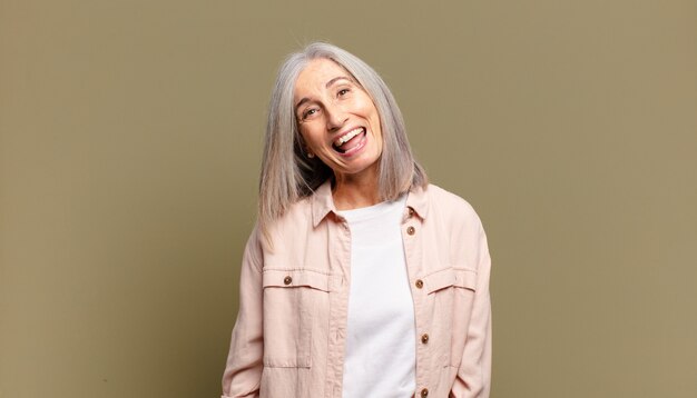 Mulher idosa com um sorriso grande, amigável e despreocupado, parecendo positiva, relaxada e feliz, arrepiante