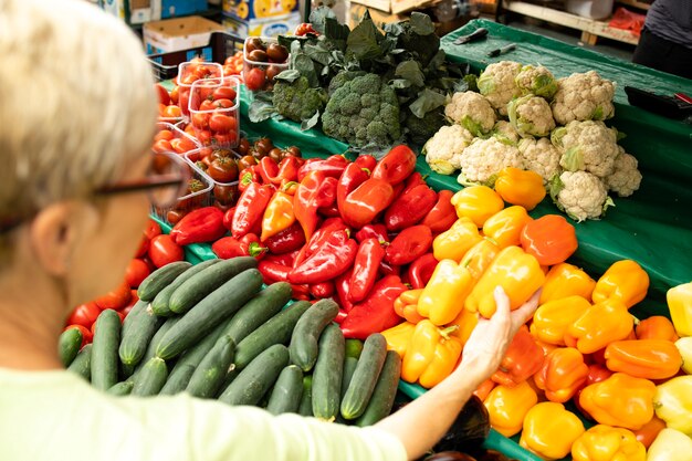 mulher idosa comprando vegetais orgânicos frescos no mercado e segurando uma sacola cheia de alimentos saudáveis