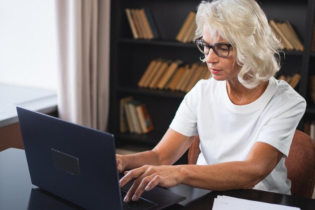 Mulher idosa confiante e elegante de meia-idade usando laptop no local de trabalho mulher de negócios mais madura