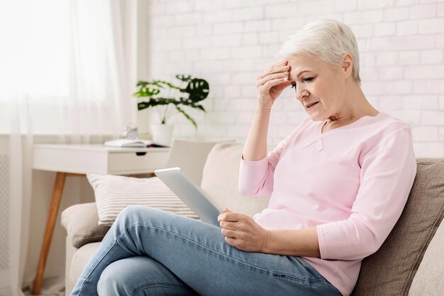 Foto mulher idosa confusa usando computador tablet parecendo desapontada não entende aparelhos modernos