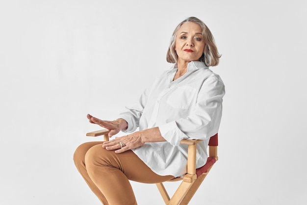 Mulher idosa de camisa branca sentada em uma cadeira closeup estilo de vida