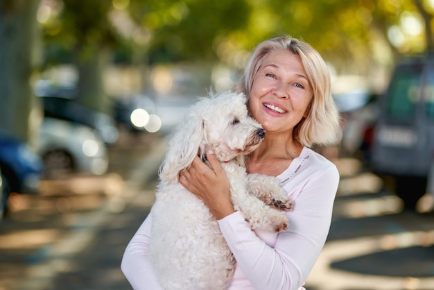 Mulher idosa de retrato com um cachorro ao ar livre.