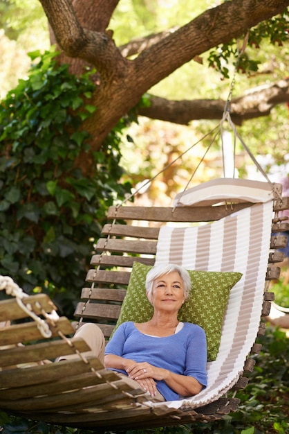 Mulher idosa e aposentadoria no jardim durante as férias de verão é motivação para felicidade para visão Pessoa idosa e árvore enquanto pensa na primavera está calma no ambiente com um sorriso