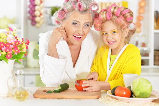 Mulher idosa e neta na cozinha com legumes