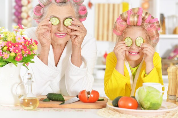 Mulher idosa e neta na cozinha com legumes