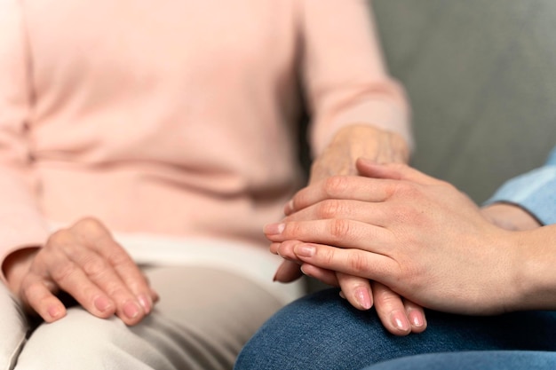 Mulher idosa e seu cuidador de mãos dadas vista de perto Enfermeira expressa cuidado como apoio psicológico para senhora aposentada