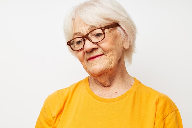 Mulher idosa emocional em camiseta casual e óculos de fundo claro