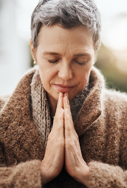 Mulher idosa está rezando de mãos dadas com adoração e religião Deus com paz gratidão e fé ao ar livre Pessoa espiritual do sexo feminino na natureza com o rosto olhos fechados e oração por orientação e bênção